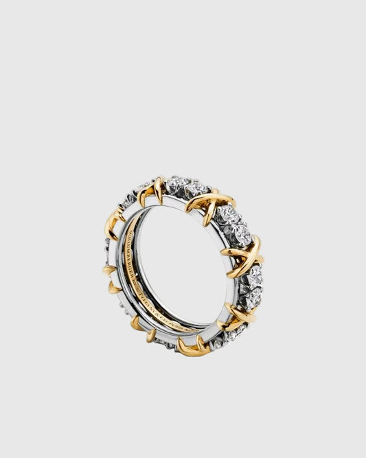 Angled studio shot of the Aurelia XVI ring showcasing the alternating round brilliant-cut moissanite gemstones and 18K gold-plated cross-stitch X motifs on a solid silver band.