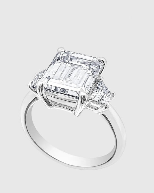 Angled studio shot of the 18K white gold-plated 925 silver ring, highlighting the massive 5-carat emerald-cut moissanite and the flawless tapered baguette side stones.