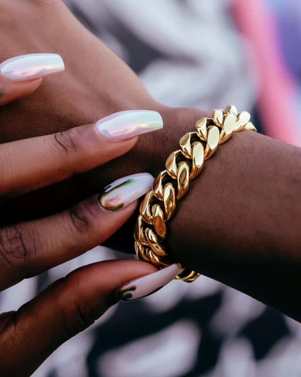 Gold chain bracelet on a wrist with a blurred background