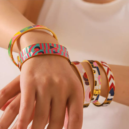 Hand wearing multiple colorful bracelets on a light background
