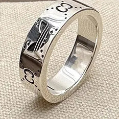 Silver ring with engraved design on a textured surface