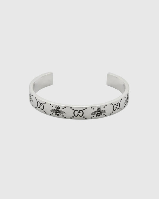 Elegant open cuff silver bracelet with engraved logo pattern, luxury minimalist bangle for women, high-end jewelry close-up