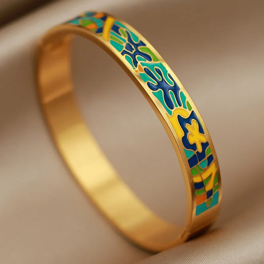 Gold bracelet with colorful enameled design on a beige background