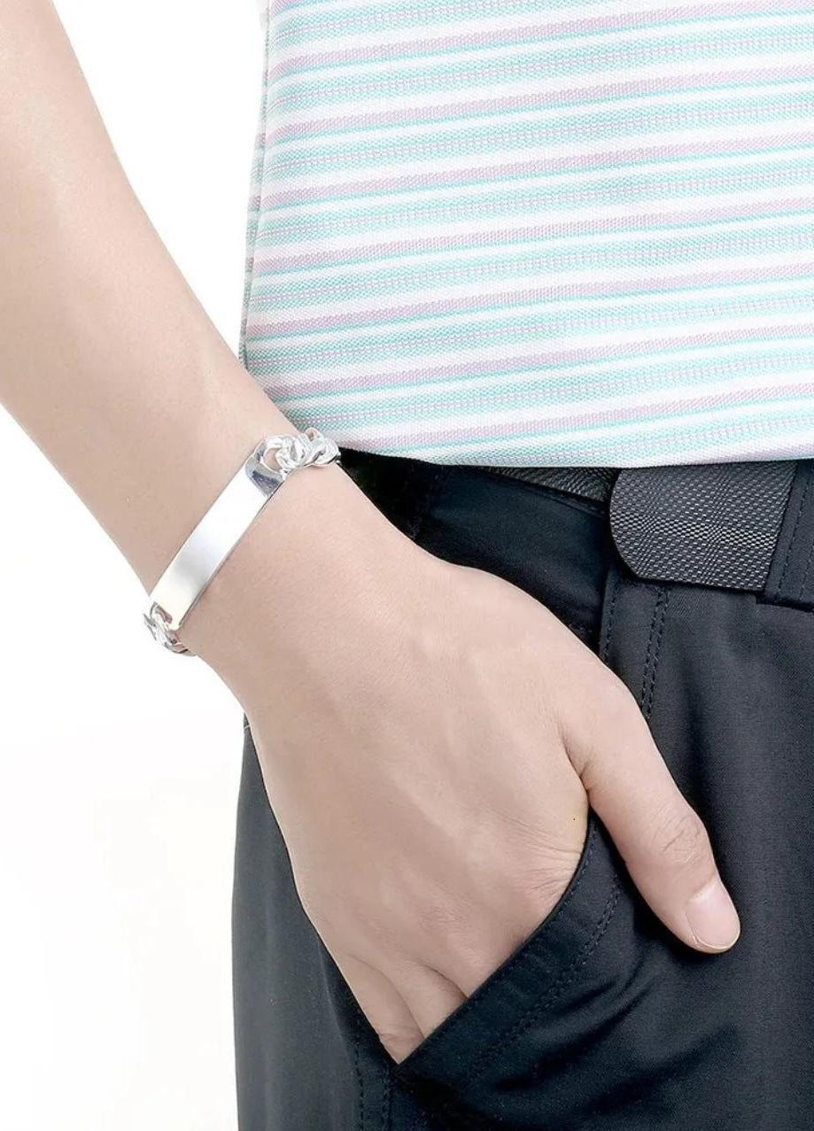 Silver Cuban Link bracelet on a wrist with a blurred background