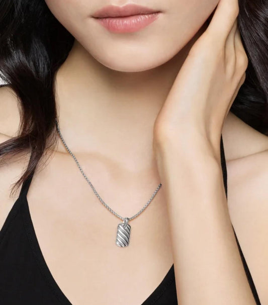 Woman wearing a silver necklace with a pendant, close-up of neck and hand.