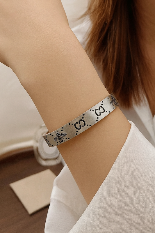 Silver bracelet with a pattern worn on a wrist, blurred background