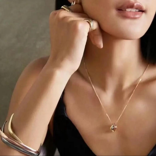 Woman wearing gold jewelry including a necklace, bracelet, and ring.