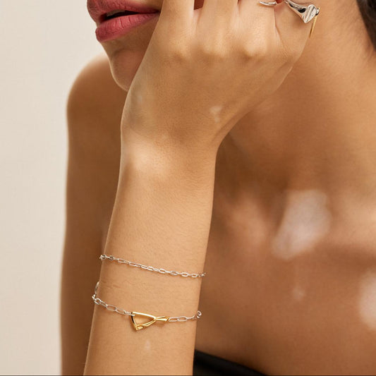 Woman wearing multiple gold and silver rings and bracelets on a neutral background