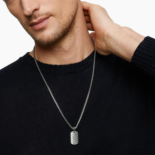 Man wearing a silver necklace with a pendant on a white background