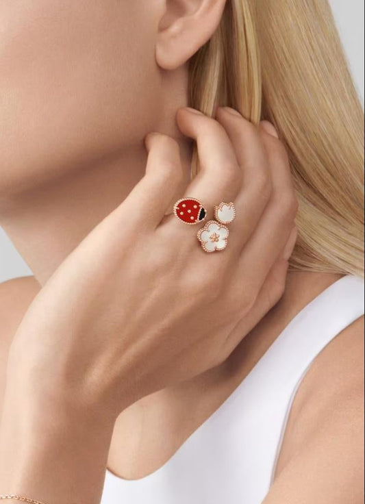 Woman wearing a bracelet and earrings with ladybug designs on a neutral background