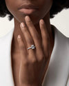 A close-up of a woman's hand wearing the spectacular 4-carat emerald-cut moissanite engagement ring featuring a U-cut pavé band in solid 18K white gold-plated silver.