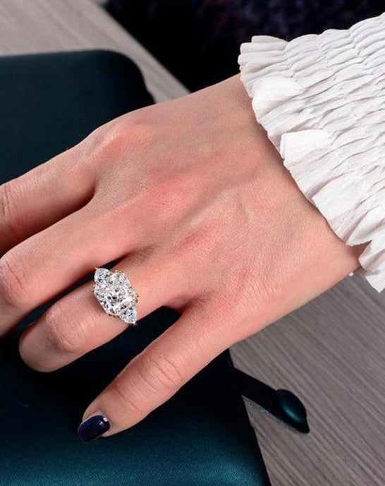 A sophisticated woman modeling the Aerion Imperia 4-carat princess-cut lab-grown diamond three-stone ring on her hand, highlighting the massive 10x10mm center stone.