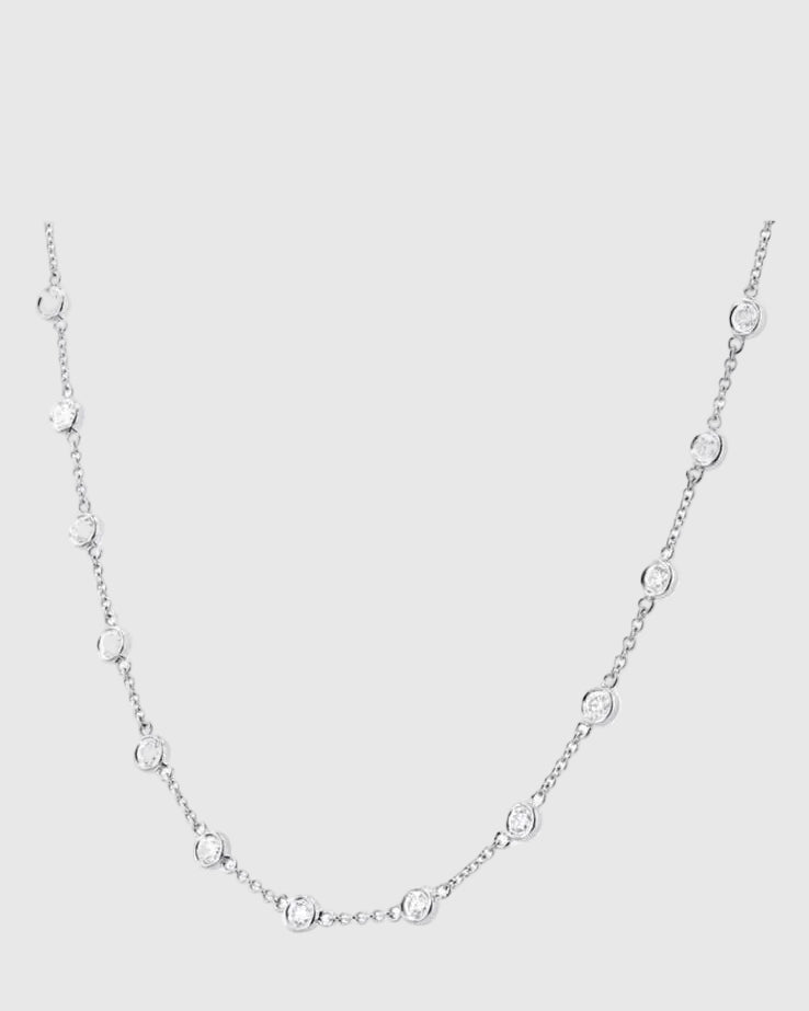 Detailed drape view of the platinum-finished Auréclaire 925 silver station necklace, capturing the brilliant light reflection and excellent cut of the moissanite stones.