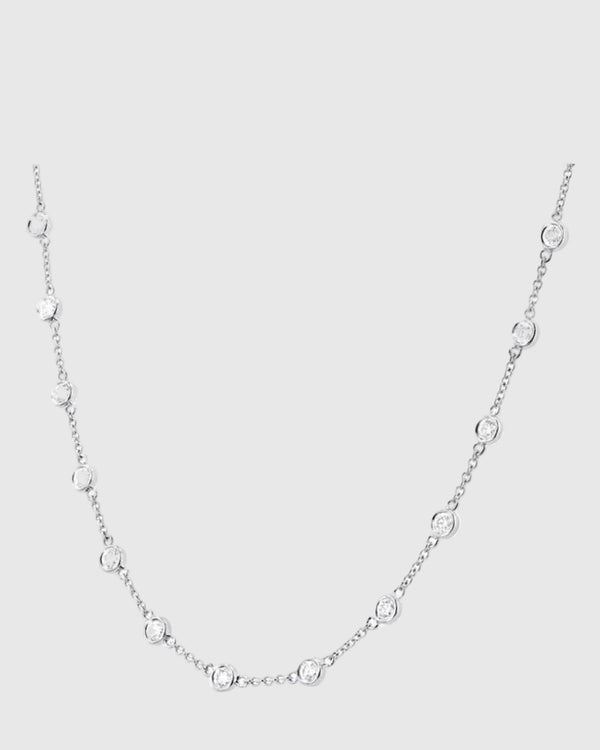 Detailed drape view of the platinum-finished Auréclaire 925 silver station necklace, capturing the brilliant light reflection and excellent cut of the moissanite stones.