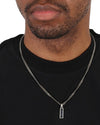 A Man's elegantly wearing the Aerion Monogram 925 silver Tag Necklace, features a sleek rectangular pendant inlaid with deep black enamel.
