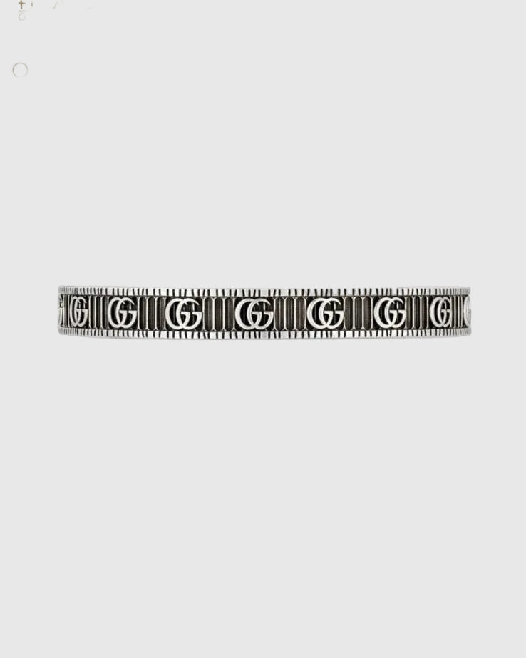 Designer silver cuff bracelet with repeating logo engraving and textured ribbed finish, open bangle luxury jewelry close-up