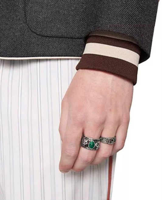 A hand wearing a 925 solid silver statement ring with malachite green stone and sculpted feline head.