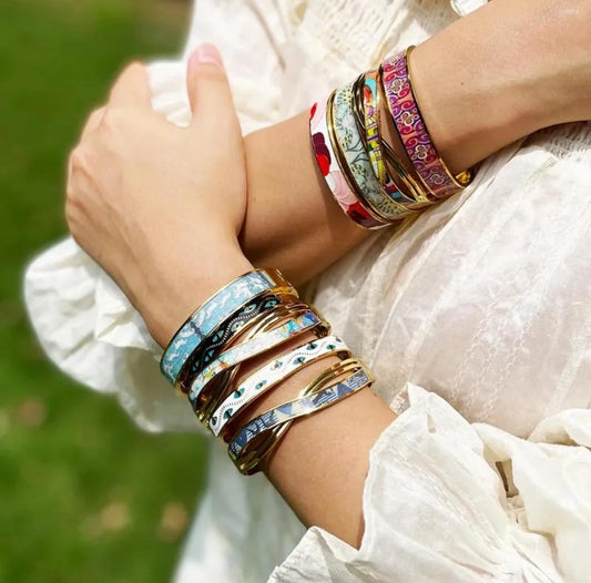 Close-up of a person's arm wearing multiple colorful bracelets with a blurred green background.