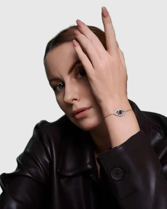 A sophisticated woman in a dark leather jacket elegantly posing with her hand near her face, wearing the Aerion Oculus solid 925 silver protective talisman bracelet featuring a 1-carat black moissanite center stone.