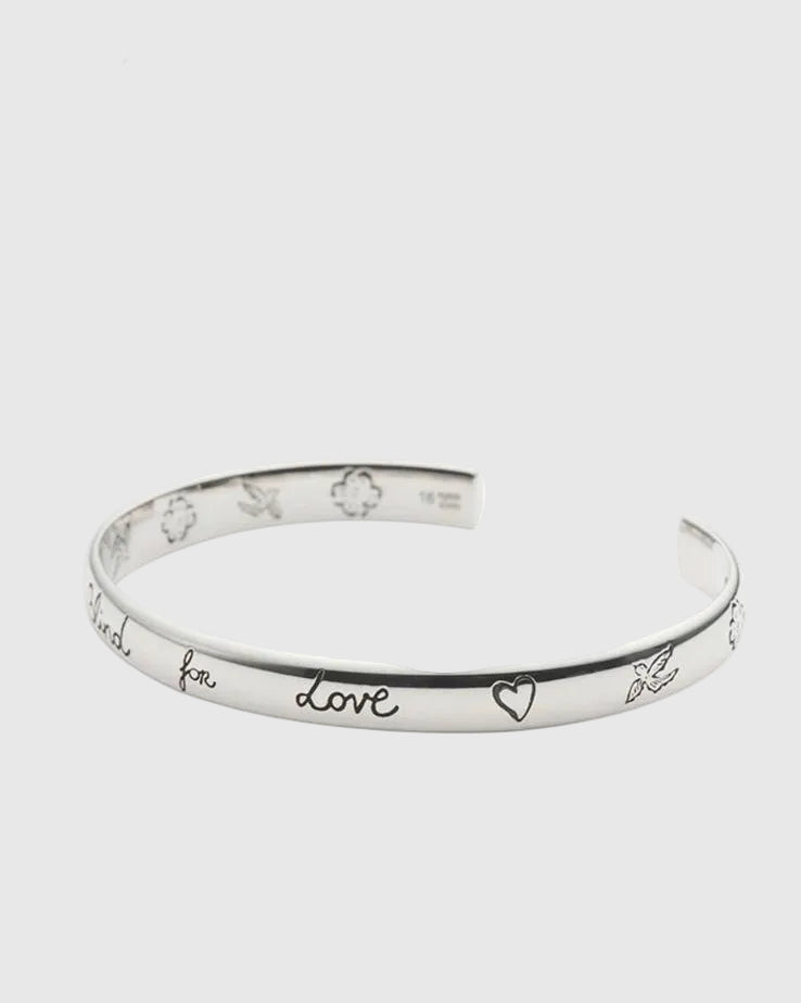 Silver bracelet with engraved text on a white background.