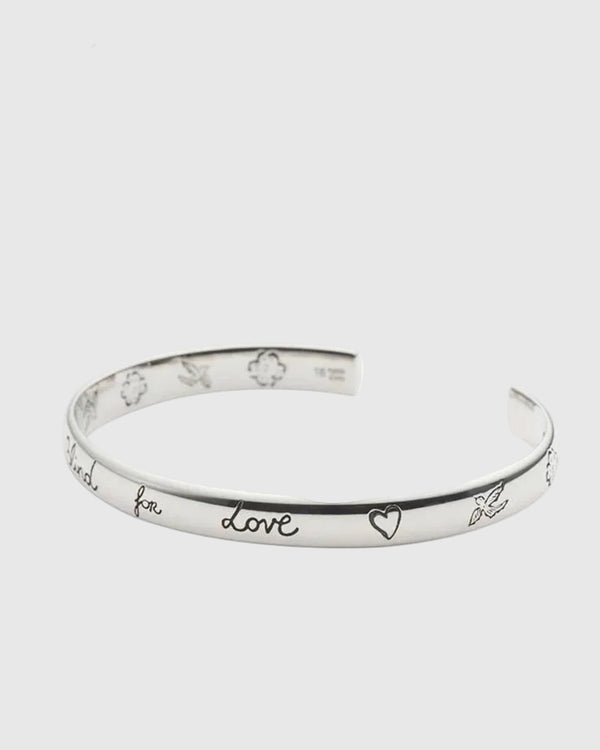 Silver bracelet with engraved text on a white background.