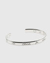 Silver bracelet with engraved text on a white background.