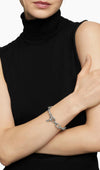 A sophisticated female model wearing a black off-shoulder top, styling the Claspéra Madison 11mm chunky 925 silver chain bracelet with the toggle clasp.