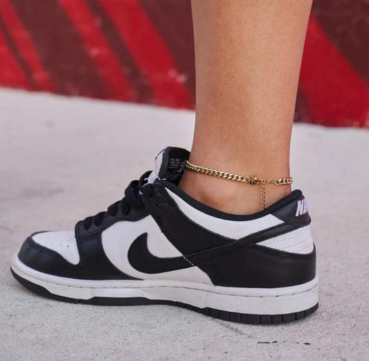 Close-up of a person wearing a silver Cuban Link Anklet with a blurred background