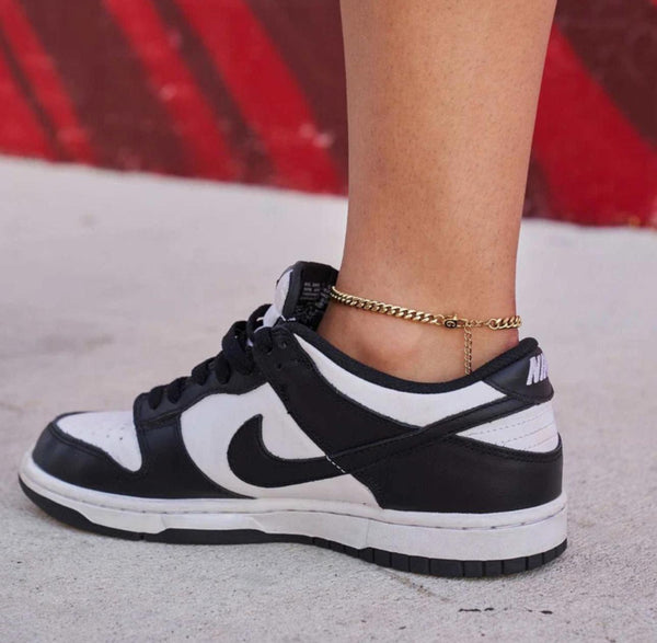Close-up of a person wearing a silver Cuban Link Anklet with a blurred background