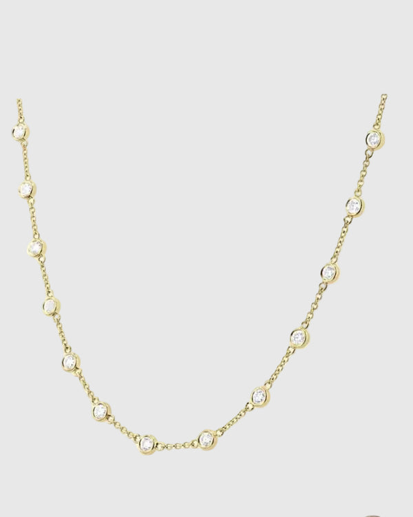 Detailed drape view of the 18K gold-plated Auréclaire station necklace, emphasizing the continuous fiery sparkle of the 20 bezel-set moissanite gemstones.