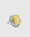 Close-up of the blue and green nano-crystal pavé halo surrounding a large yellow gemstone on a silver ring.
