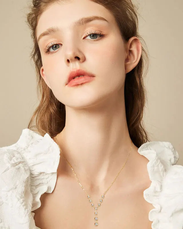 A beautiful model in a white ruffled top wearing the 18K gold-plated 925 silver moissanite Y-necklace, highlighting the elegant lariat drop resting gracefully on her collarbone.
