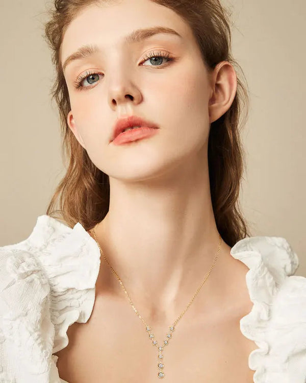 A beautiful model in a white ruffled top wearing the 18K gold-plated 925 silver moissanite Y-necklace, highlighting the elegant lariat drop resting gracefully on her collarbone.
