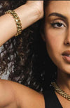 Woman wearing a gold chain necklace and bracelet with a neutral background