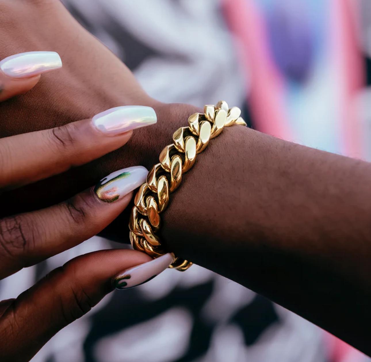 Gold chain bracelet on a wrist with a blurred background