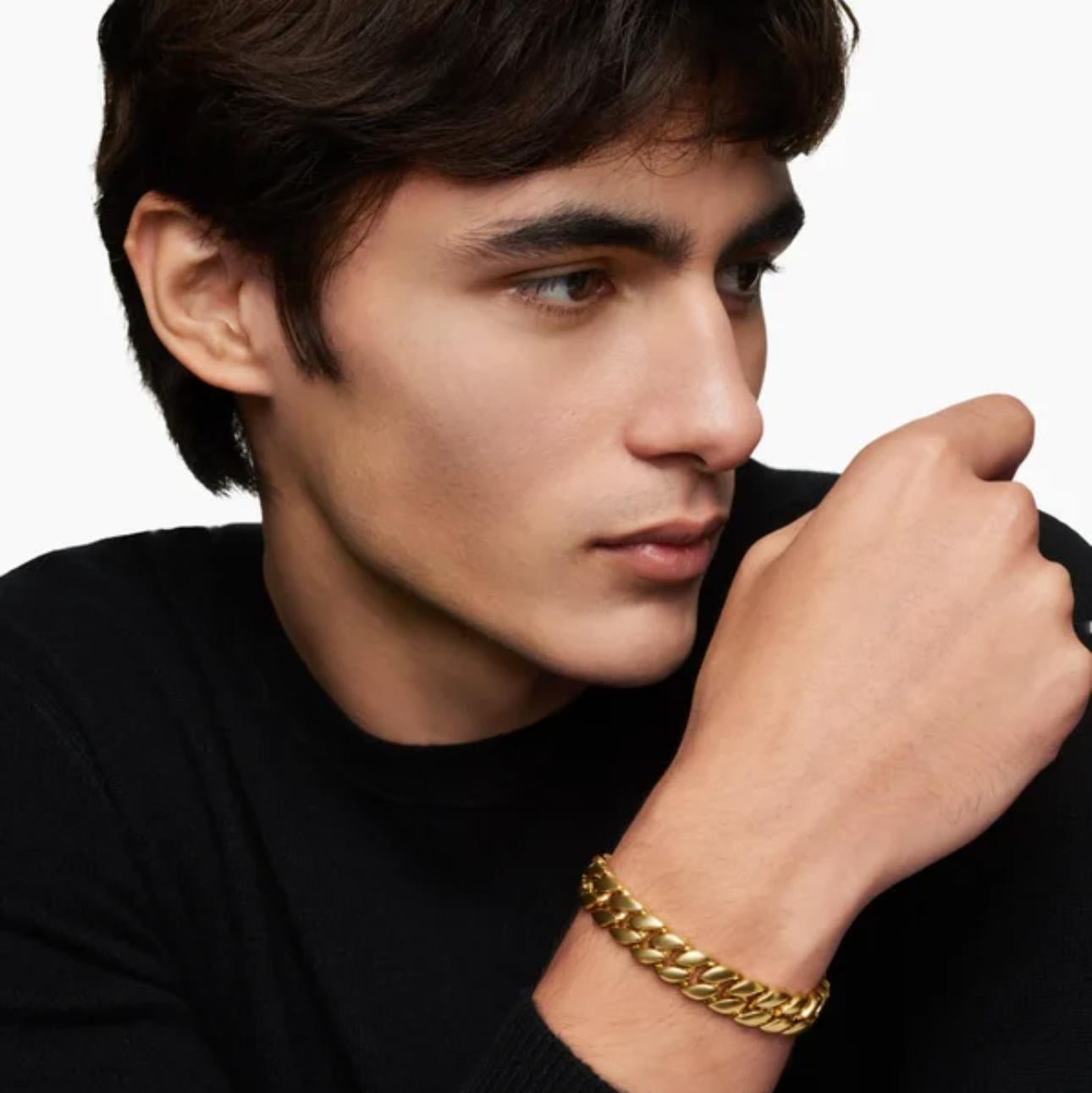 Man wearing a black sweater with a Gold Curb Chain Bracelet on a plain background