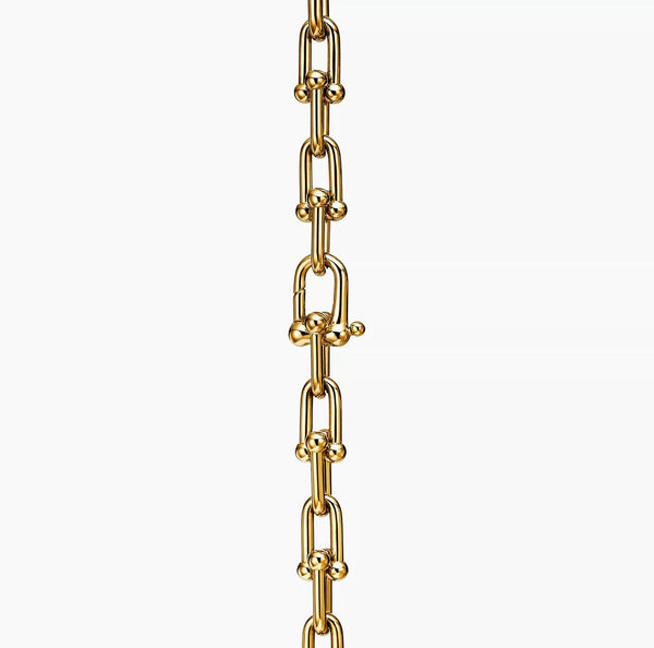 Close-up of a gold horseshoe-link chain showing the hidden push-lock clasp integrated within the rounded links.