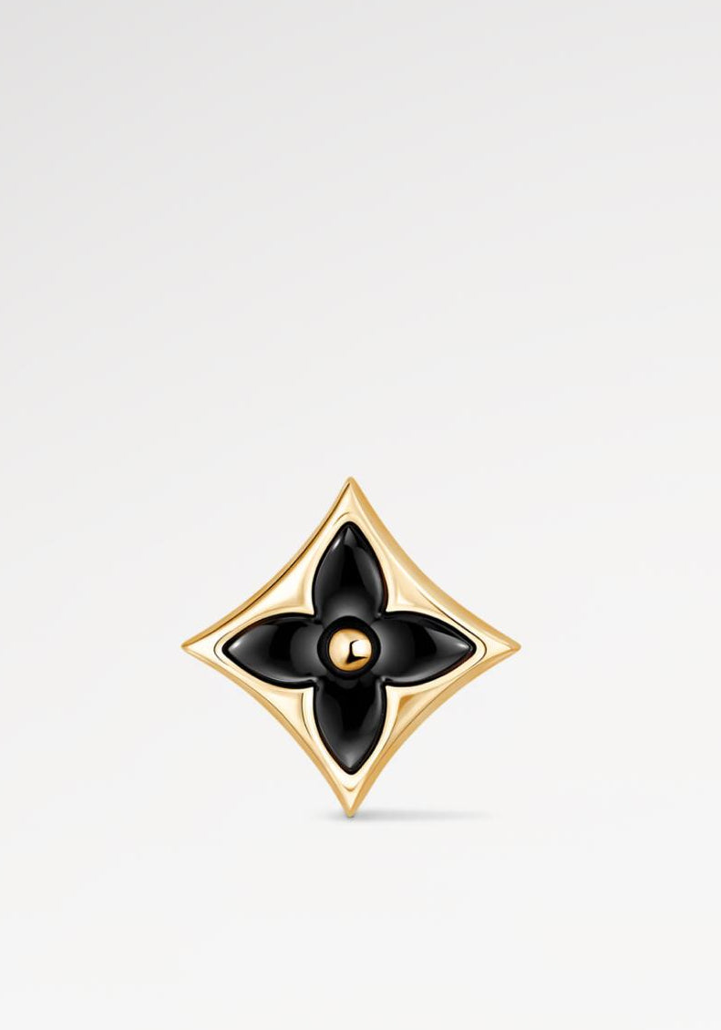 Gold and black Star Ear Stud on a light gray background