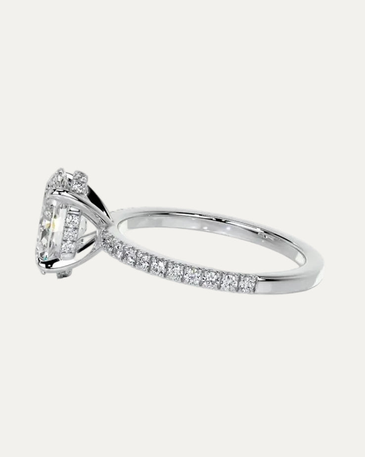 Extreme close-up side profile of the engagement ring revealing the secret hidden halo of 20 micro-pavé stones, the shared-prong U-cut gallery, and the wedding-ring friendly raised bridge.