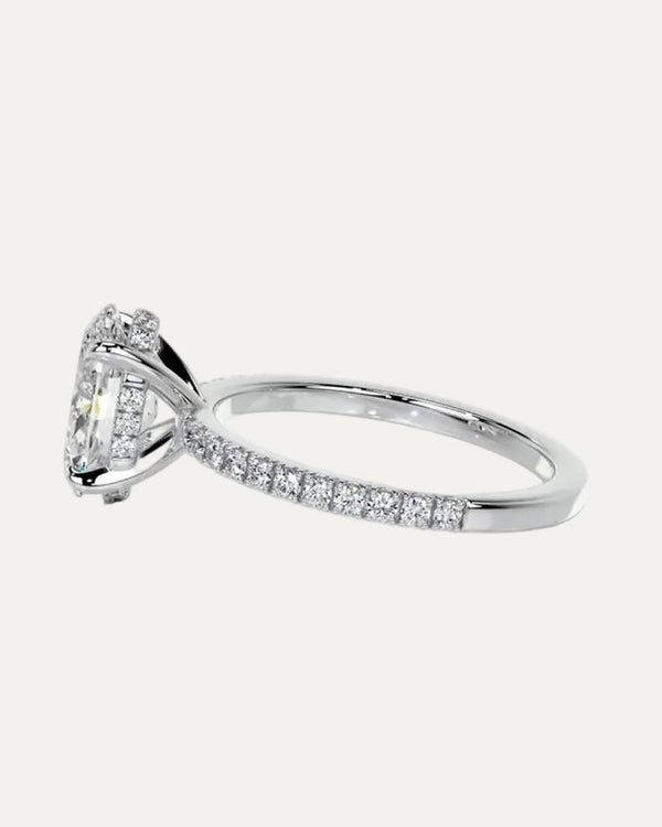 Extreme close-up side profile of the engagement ring revealing the secret hidden halo of 20 micro-pavé stones, the shared-prong U-cut gallery, and the wedding-ring friendly raised bridge.