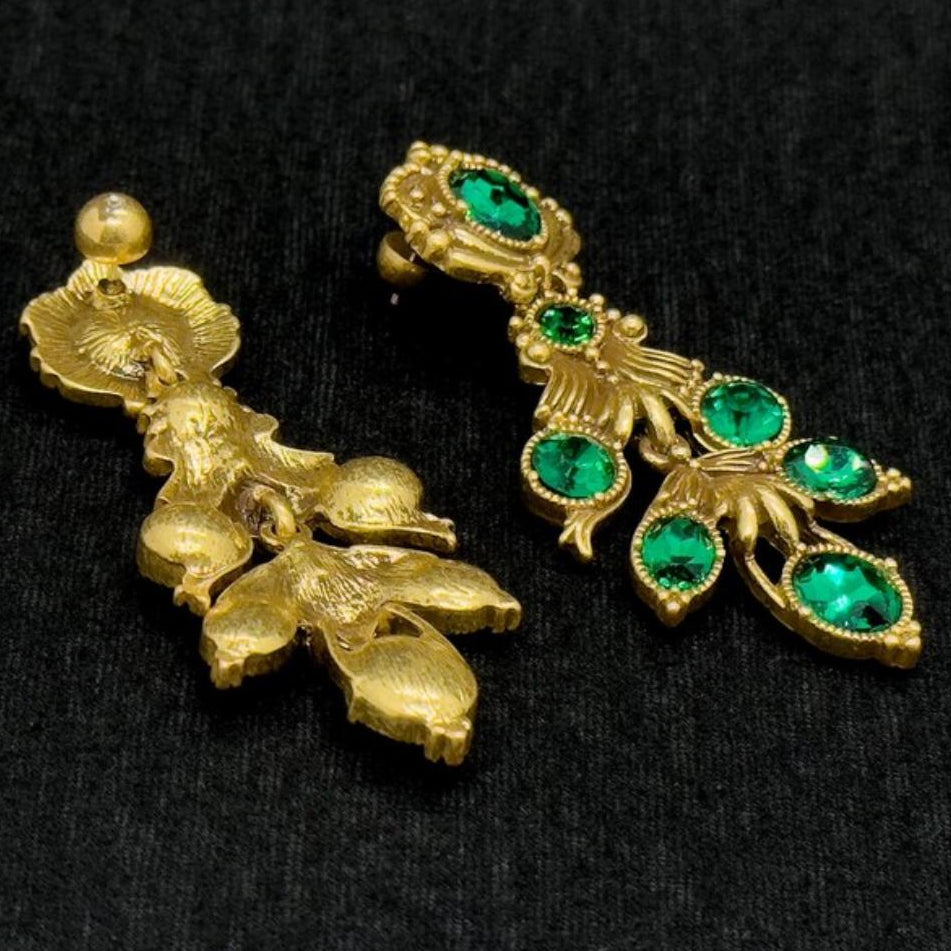 Gold earrings with green gemstones on a black background
