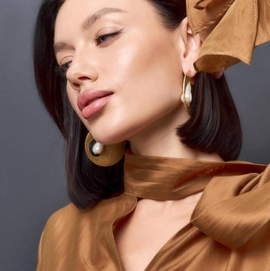 Woman wearing a brown outfit with a matching headscarf against a gray background
