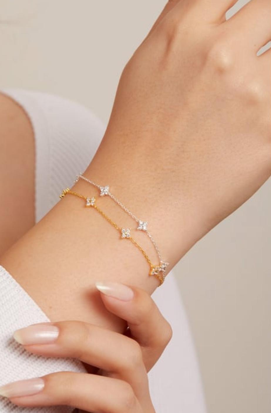 Gold bracelet with small diamonds on a wrist against a neutral background