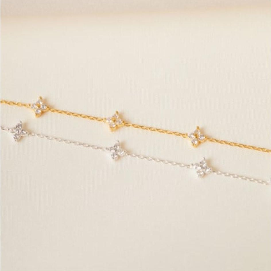Gold and silver bracelet with star-shaped charms on a light beige background