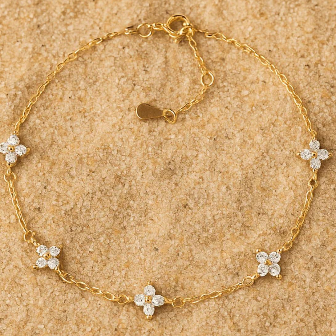 Gold bracelet with floral charms on a beige background