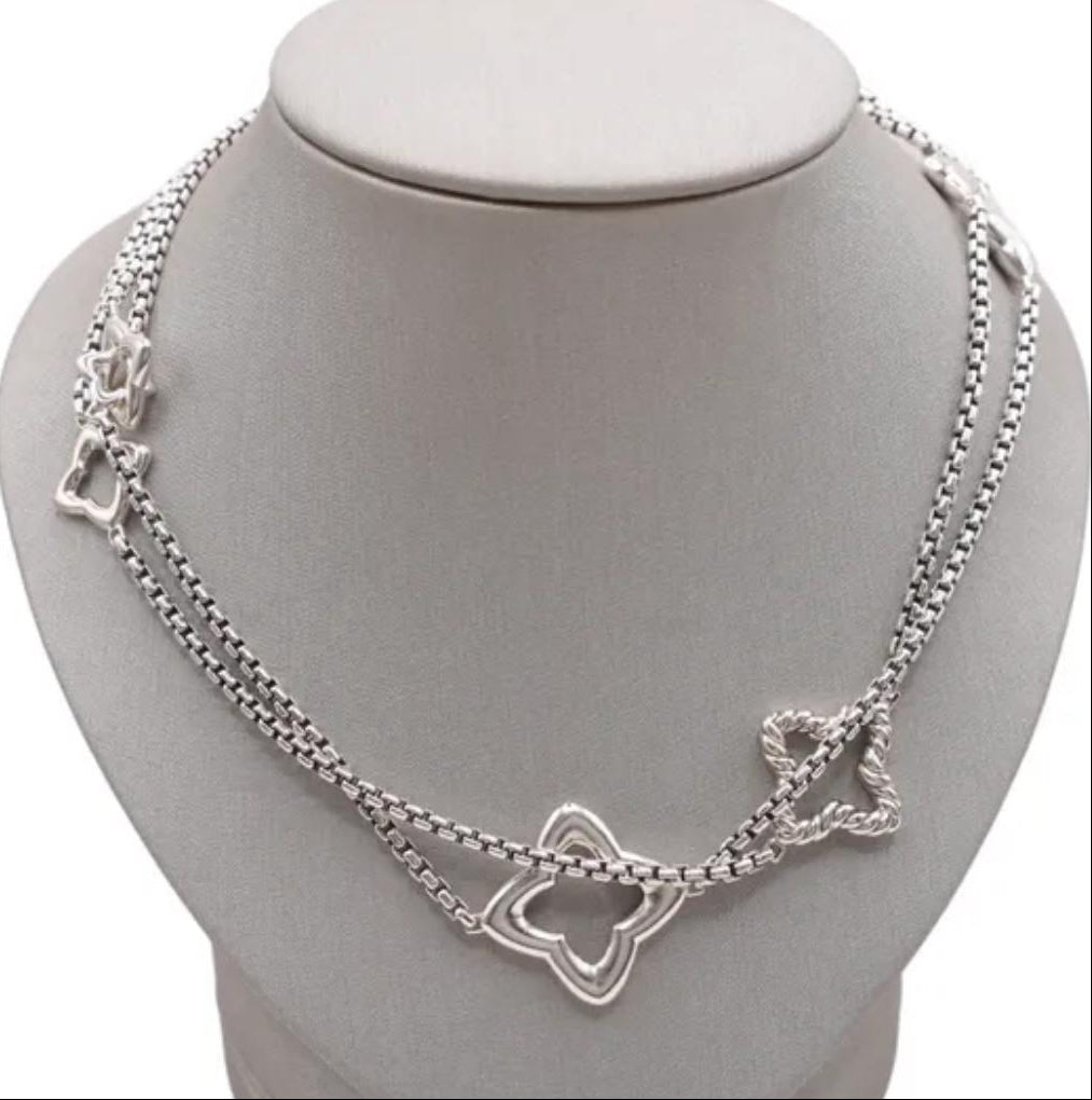 Silver necklace with butterfly designs on a gray stand