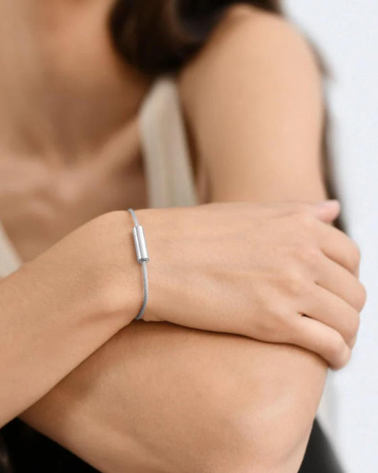 Woman wearing a silver bracelet on a plain background