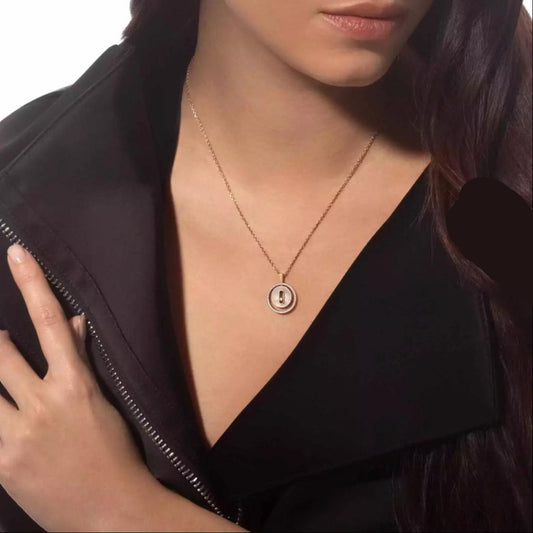 Person wearing a gold necklace with a round pendant on a white background