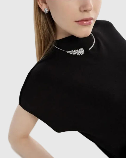A luxury editorial photo of a model wearing the L’Éthérée peacock feather necklace and matching diamond earrings, showcasing a quiet luxury aesthetic.