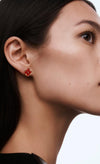 Close-up of a woman wearing red earrings on a plain background